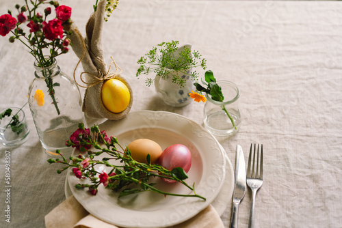 Happy Easter. Stylish easter eggs on a napkin with spring flowers on white wooden background. Table setting. The concept of a happy Easter holiday.
