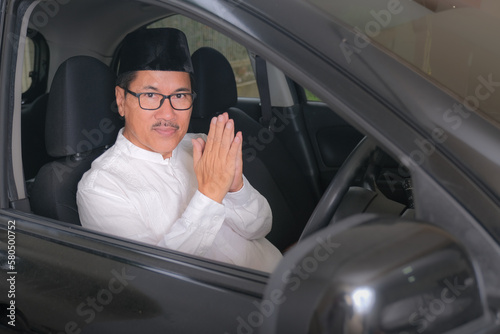 Indonesian moslem man solemnly greet from inside his car cabin. photo