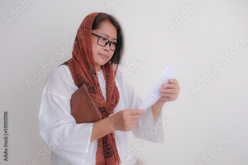 Housewife looks unhappy to see her shopping list in her hand photo
