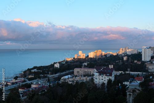 View of Sochi city on a sunny winter day with bright blue sky with white clouds and blue sea during beautiful sunrise. Nature background with selective focus. Travel concept