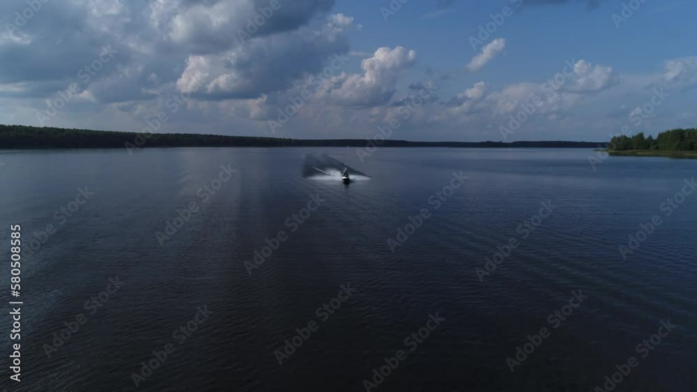 The jet ski is moving fast along a wide river. Sports water recreation on the weekend. An aquabike racer. The jet ski is moving fast along a wide river. Sports water recreation on the weekend. An aquabike racer.