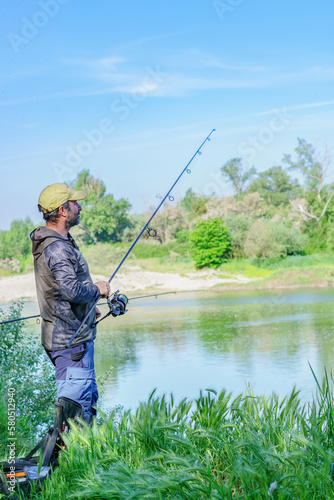 angler on the river bank with rod in hand fishing for carp