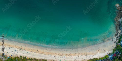 aerial top view above white sand beach. beach crowded with tourists..turquoise sea at Nai Harn beach Phuket. 4k colorful blue sea background..beautiful nature background..