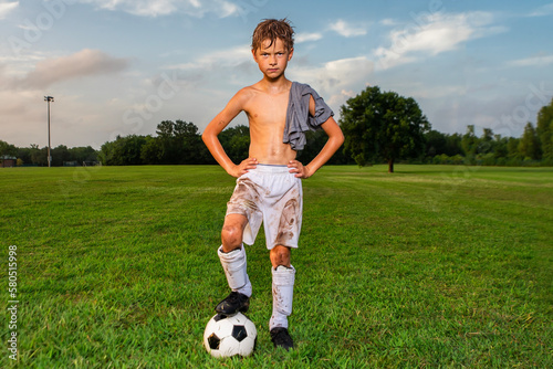 Hot and sweaty young soccer player posing with shirt off after soccer game