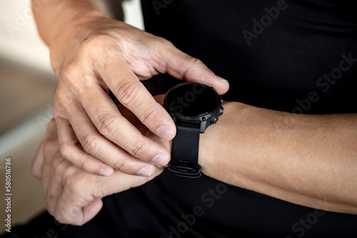 Sport man checking workout result on smartwatch app after exercise session in fitness gym. Wearable device or personal fitness tracker. Smart watch technology for health tracking and physical activity