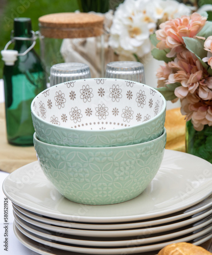 pile de bols verts et d'assiettes blanche en porcelaine sur une table avec des accessoires décoratifs autour photo