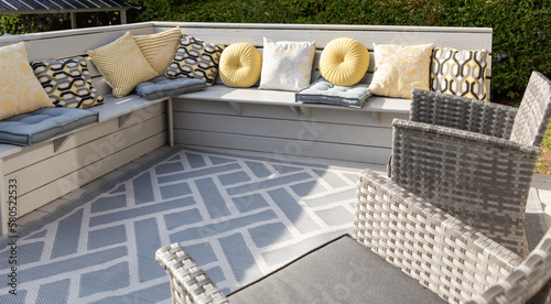 vue sur un espace de jardin avec du mobilier d'extérieur avec coussins gris et jaune photo