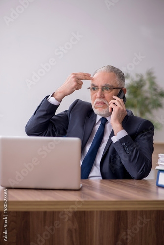 Old male employee working in the office