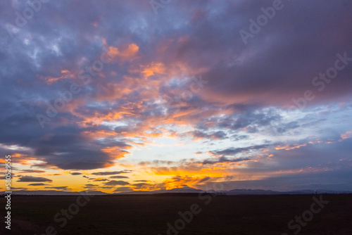 blue and colorful clouds at the sky during sundown n a flat landscape © thomaseder