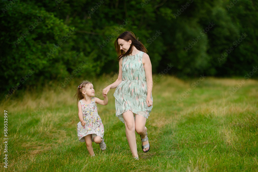 Fototapeta premium Portraits of joyful mother and daughter spend time together, enjoy happy family time, run in the park. Mother's day.