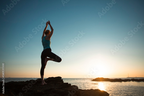 Yoga women silhouette on the Atlantic shore during an amazing sunset.