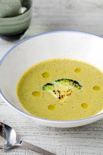 Healthy broccoli soup with a slice of grilled broccoli on a white porcelain plate