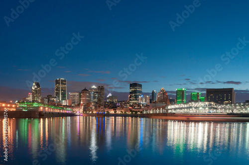 Illuminated modern buildings by Saint Lawrence River against sky at dusk photo