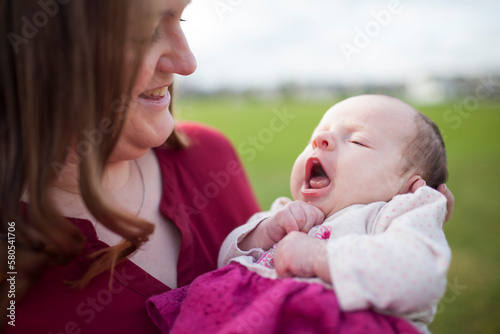 Close-up of smiling mother looking at daughter with mouth open in park photo