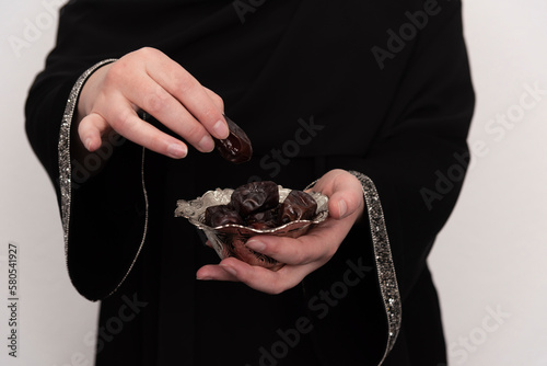 Muslim woman offering dates to friend for breaking fast, hands closeup