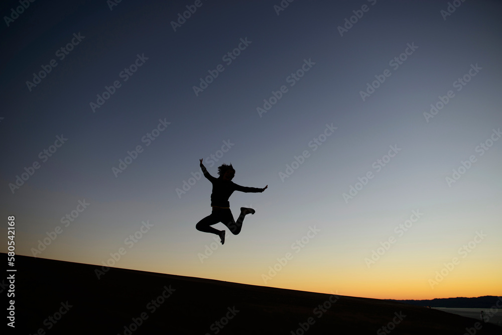 Silhouette woman jumping on land against clear sky during dusk Silhouette woman jumping on land against clear sky during dusk
