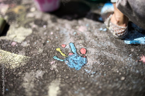Close-up of girl by handprint on asphalt during sunny day photo
