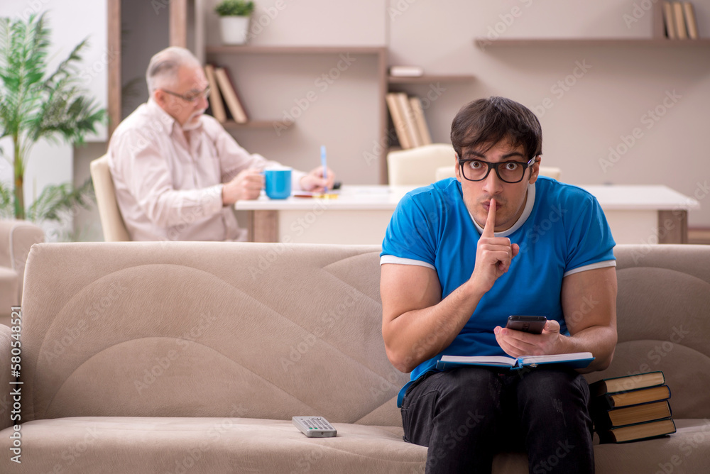 Obraz premium Young male student and his grandfather at home