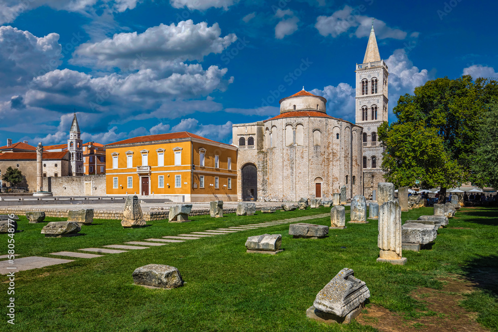Zadar, Croatia - The Roman ruins and the Forum of the old town of Zadar with the Church of St. Donatus and the bell tower of the Cathedral of St. Anastasia on a summer day with blue sky and clouds