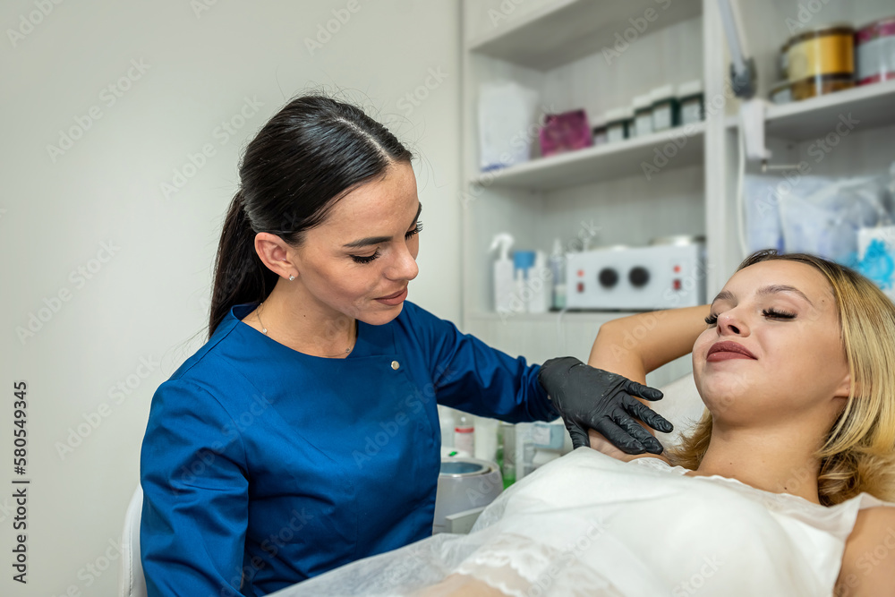 Beautician doing cosmetology procedure is removing hair in armpits with hot wax Beautician doing cosmetology procedure is removing hair in armpits with hot wax