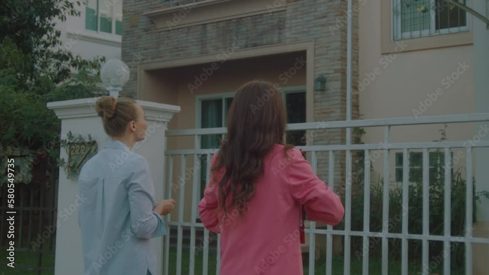A young female real estate agent in a pink business suit with documents in hand shows houses to a potential client A young female real estate agent in a pink business suit with documents in hand shows houses to a potential client