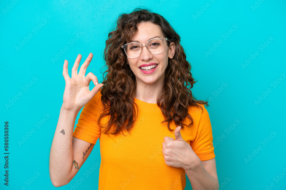 Fototapeta premium Young caucasian woman isolated on blue background With glasses and doing OK sign