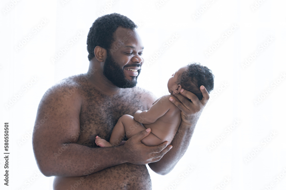 Fototapeta premium African American bearded father holding his cute newborn baby in his arms, Dad standing smiling and looking at baby, infant boy 2 months old, Family and newborn care. White background, side view