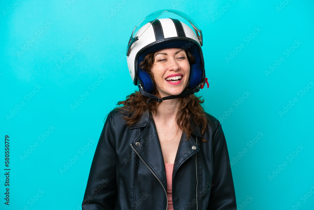 Young caucasian woman with a motorcycle helmet isolated on blue background laughing Young caucasian woman with a motorcycle helmet isolated on blue background laughing