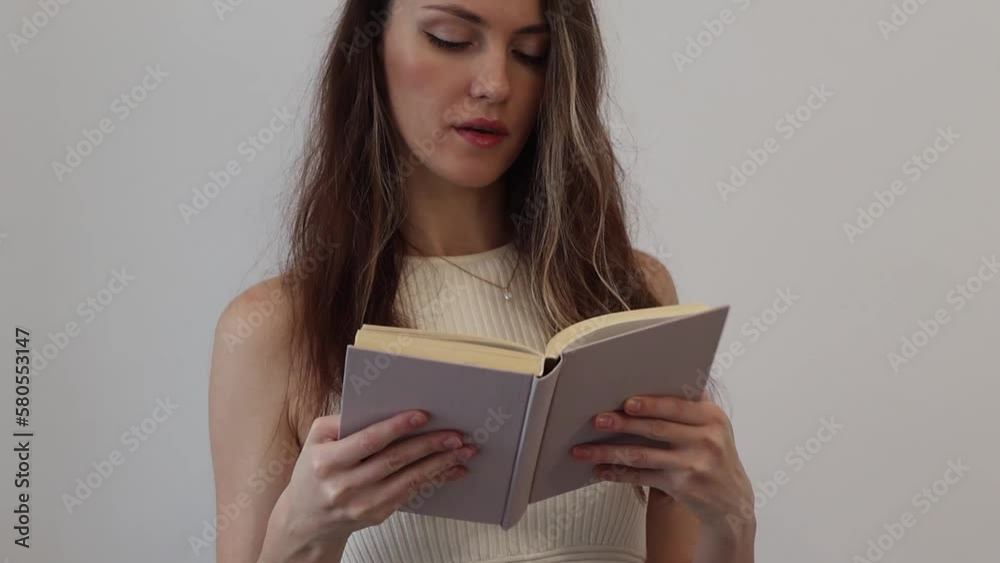 Beautiful happy young woman holding a beige book in her hands and opening it. Close-up. Beautiful happy young woman holding a beige book in her hands and opening it. Close-up.