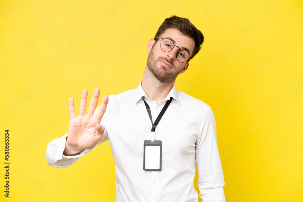 Young caucasian with ID card isolated on yellow background happy and counting four with fingers
