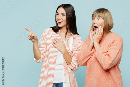 Photography Surprised elder parent mom with young adult daughter two women together in casual clothes point index finger aside on workspace area mock up isolated on plain blue cyan background