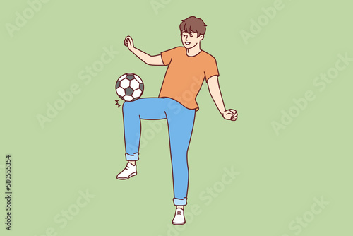 Happy man kicking soccer ball wanting to become famous major league player and compete in international sports competitions. Young promising soccer player training alone with smile doing tricks  photo