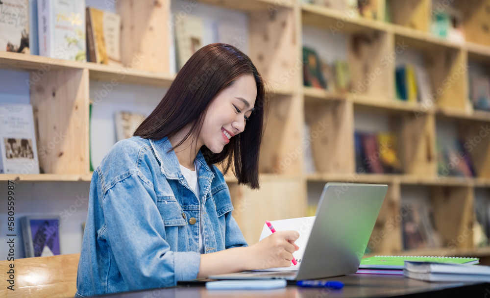 Fototapeta premium Young Asian girl studying at library