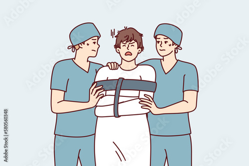 Two orderlies lead crazy man in straitjacket suffering from mental problems or schizophrenic illness. Crazy guy admitted to psychiatric hospital for treatment after seasonal exacerbation 