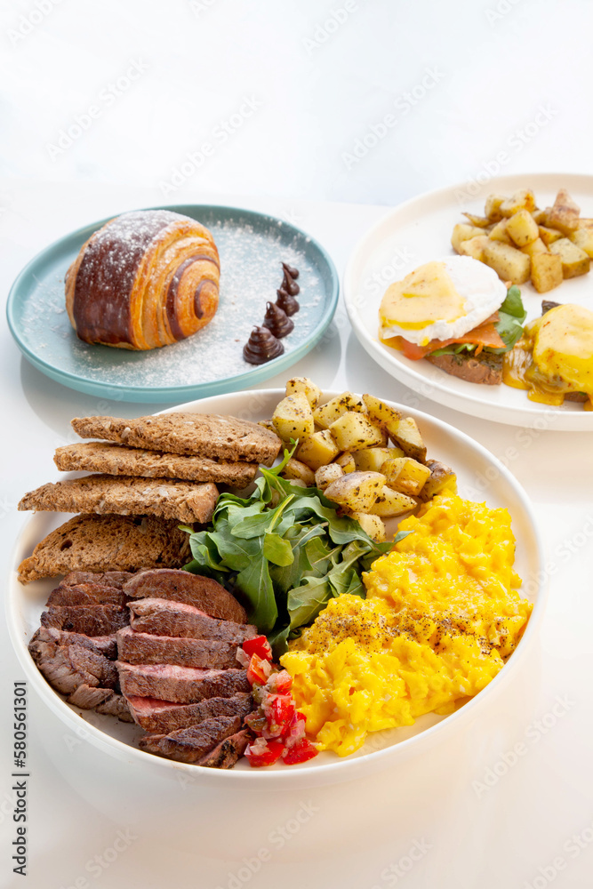 Tenderloin beef steak with scrambled eggs, rocket leaves and potatoes with a side of rye bread. Tenderloin beef steak with scrambled eggs, rocket leaves and potatoes with a side of rye bread.