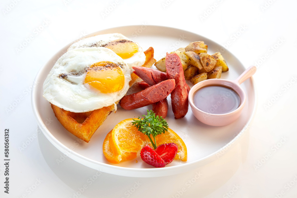 Double fried egg on waffles with maple syrup sausages and potatoes breakfast.