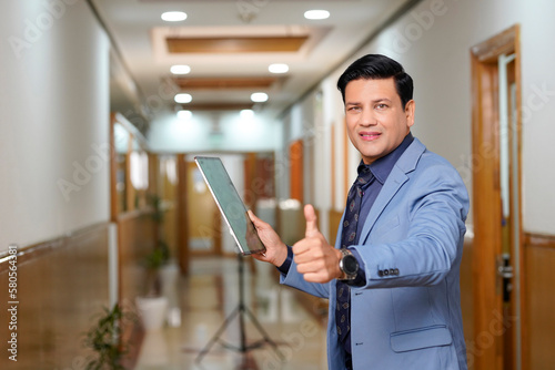Indian businessman using Digital Tablet and showing thumps up