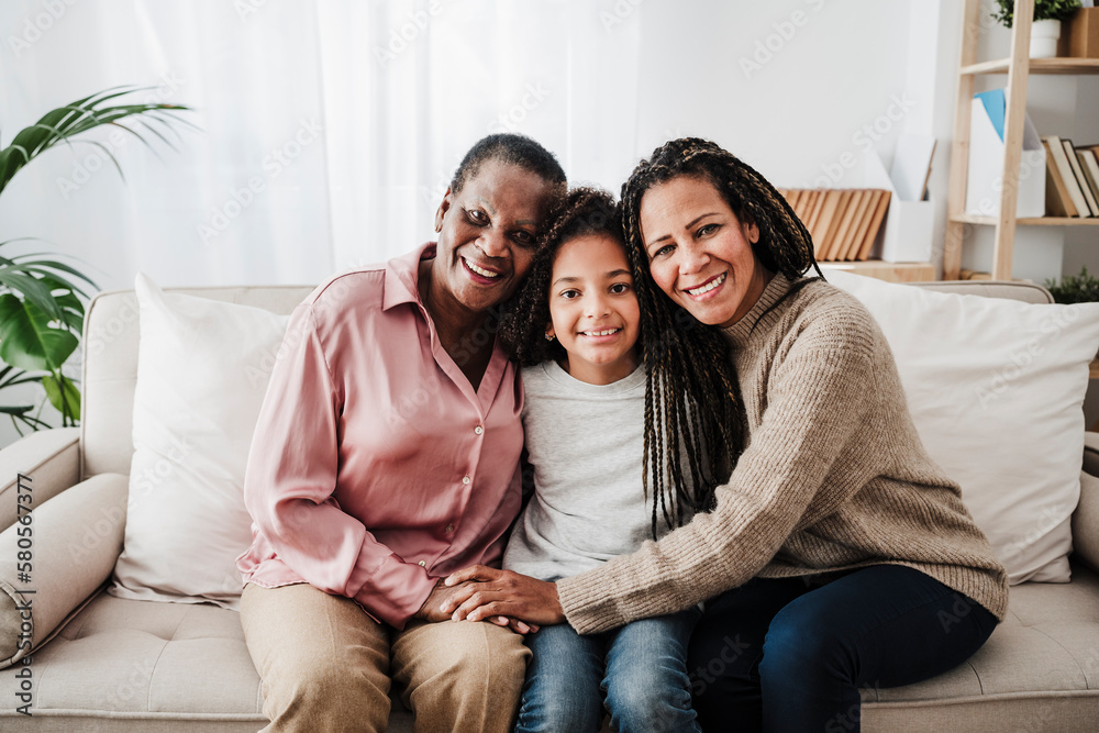 Smiling woman sitting with mother and daughter on sofa at home Smiling woman sitting with mother and daughter on sofa at home
