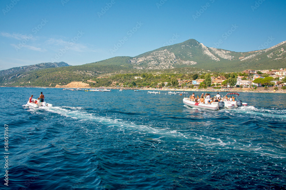 Tourist boats and dinghies leaving the port of Cala Gonone, Gulf of Orosei, Dorgali, Sardinia, Italy.