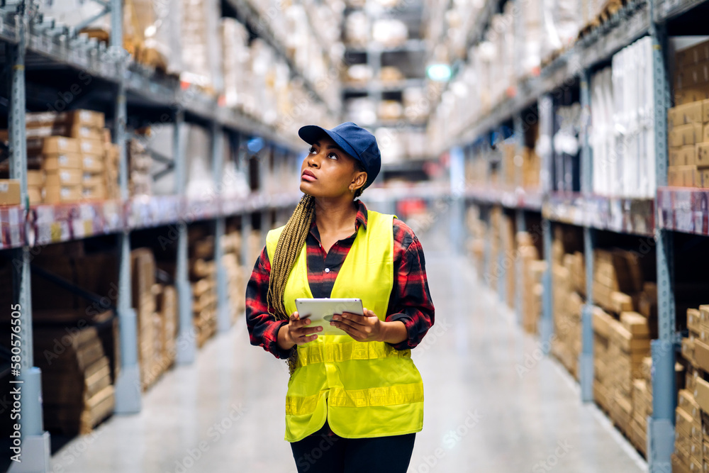 Portrait of smiling african american engineer woman order details on tablet checking goods and supplies on shelves with goods background in warehouse.logistic and business export