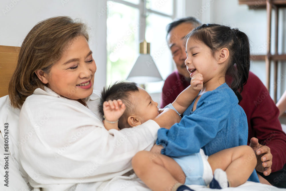 Portrait of happy love asian grandfather with grandmother playing with asian baby and little cute girl on bed.Big family love with their laughing grandparents smiling together.Family and togetherness Portrait of happy love asian grandfather with grandmother playing with asian baby and little cute girl on bed.Big family love with their laughing grandparents smiling together.Family and togetherness