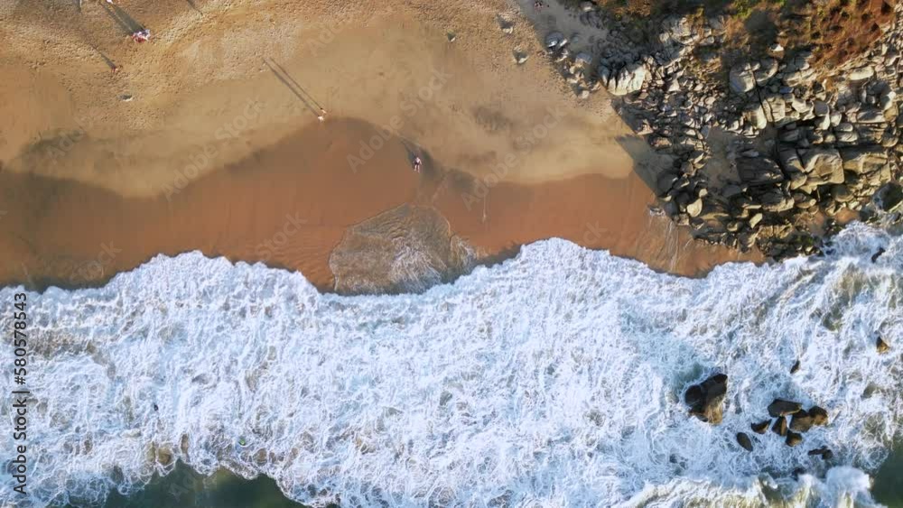 A man lays on a beach and makes sand angel in the sand as seen from an ...
