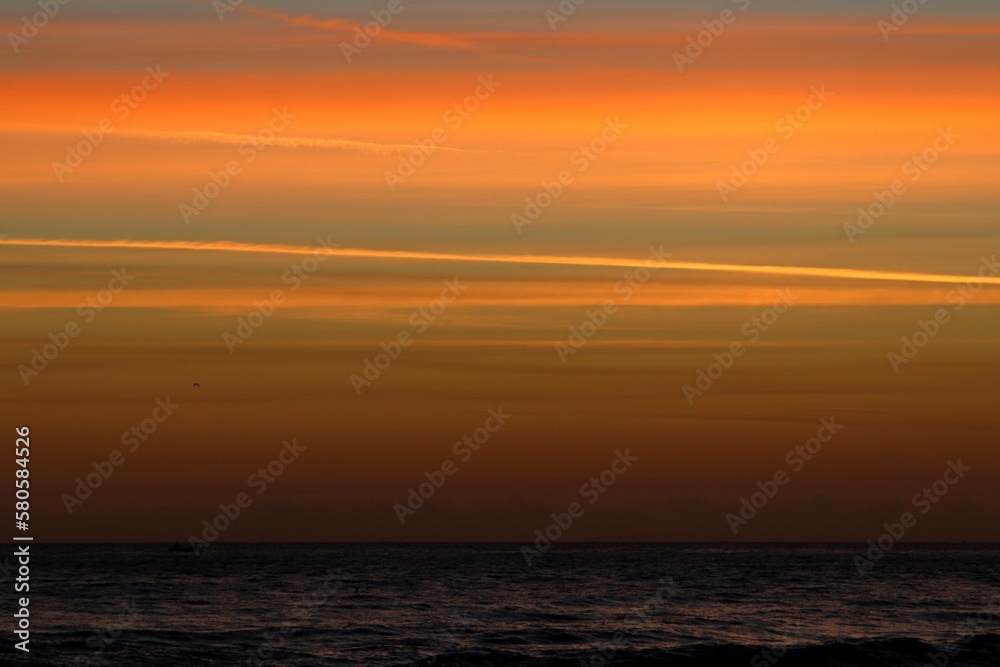 Sunrise over the ocean producing an orange and peach sky Sunrise over the ocean producing an orange and peach sky