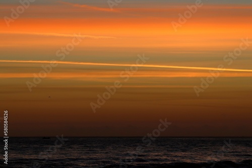 Sunrise over the ocean producing an orange and peach sky