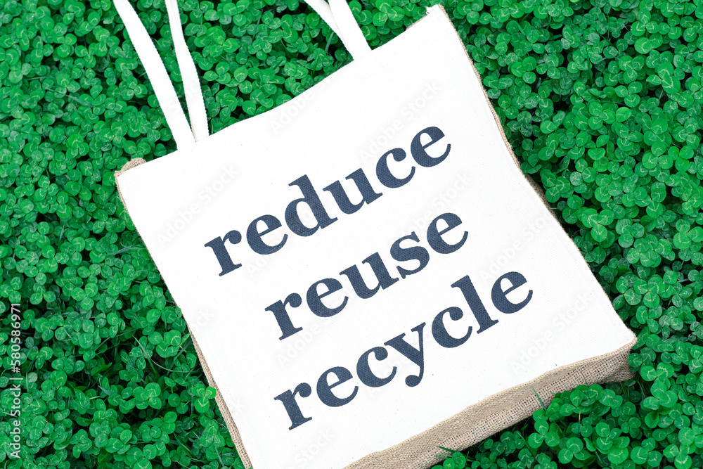 jute bag with inscription Reduce Reuse Recycle on grass. Eco friendly ...