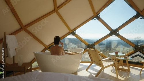 Beautiful female drinking coffee in tub  on glamping