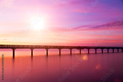 Brücke über Wasser bei Sonnenaufgang in violetter Farbstimmung