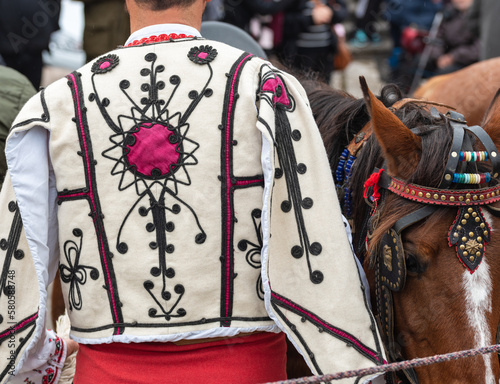 People in traditional bulgarian clothing riding a horse in the mountains photo