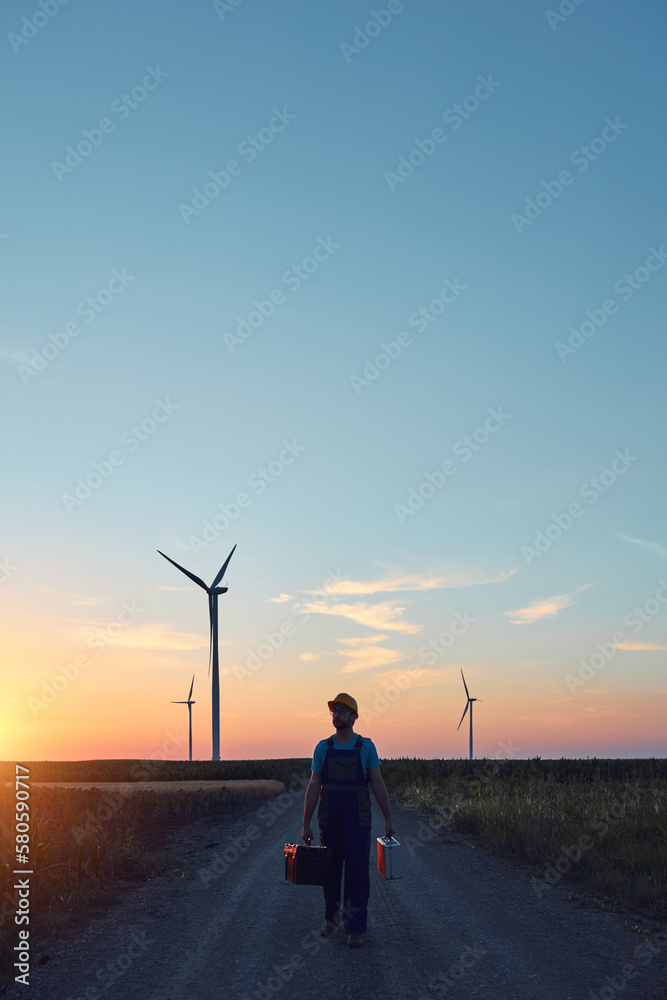 Fototapeta premium Engineer mechanic in a windmill farm park checking and servicing wind turbines.