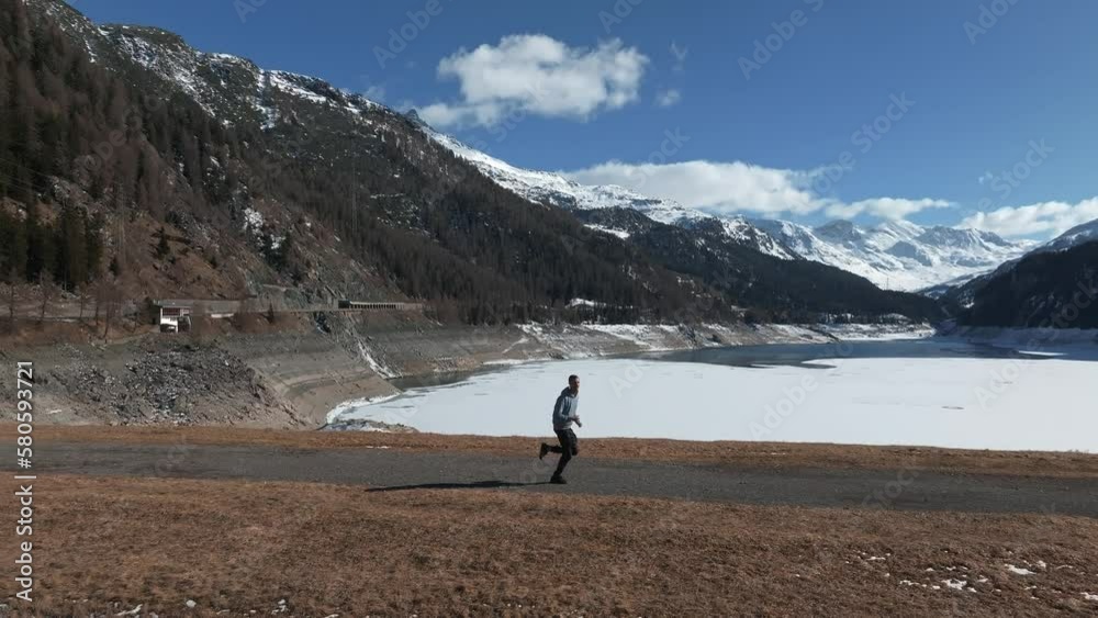 Young man running down the beautiful scenery in Switzerland. Mighty Alps in the background. Celebrating happy life. Young man running down the beautiful scenery in Switzerland. Mighty Alps in the background. Celebrating happy life.